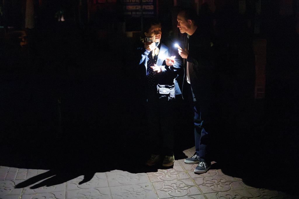 Dos pasajeros se alumbran con la luz de un mvil en la estacin de autobuses de Mndez lvaro (Madrid).